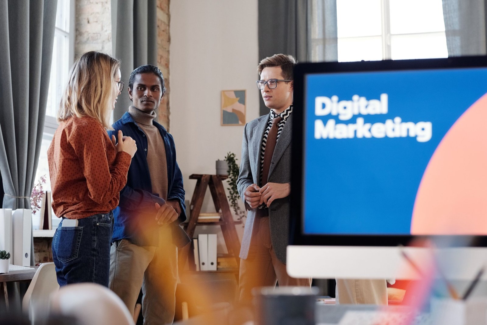Group of colleagues discussing digital marketing strategies in an office setting.